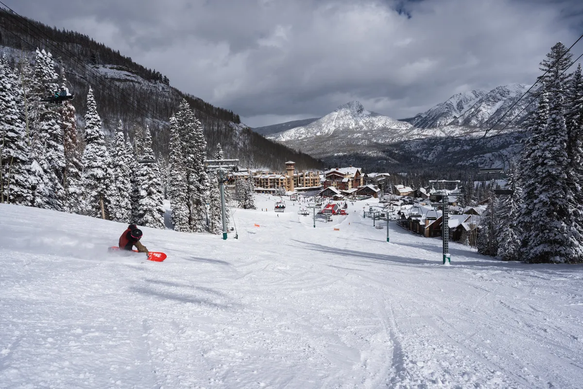 An exterior winter scene featuring a skier gliding down snow-covered slopes, with majestic mountains, ski lifts, and charming resort buildings in the background. The landscape is blanketed in fresh snow, evoking a sense of adventure and awe-inspiring natural beauty.