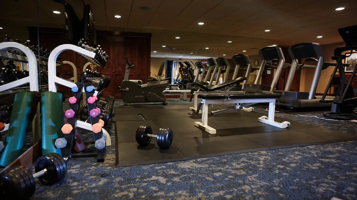 A different angle inside the fitness center, featuring exercise benches and additional workout equipment. The atmosphere is energetic and motivational, highlighting the variety of fitness options available to guests.