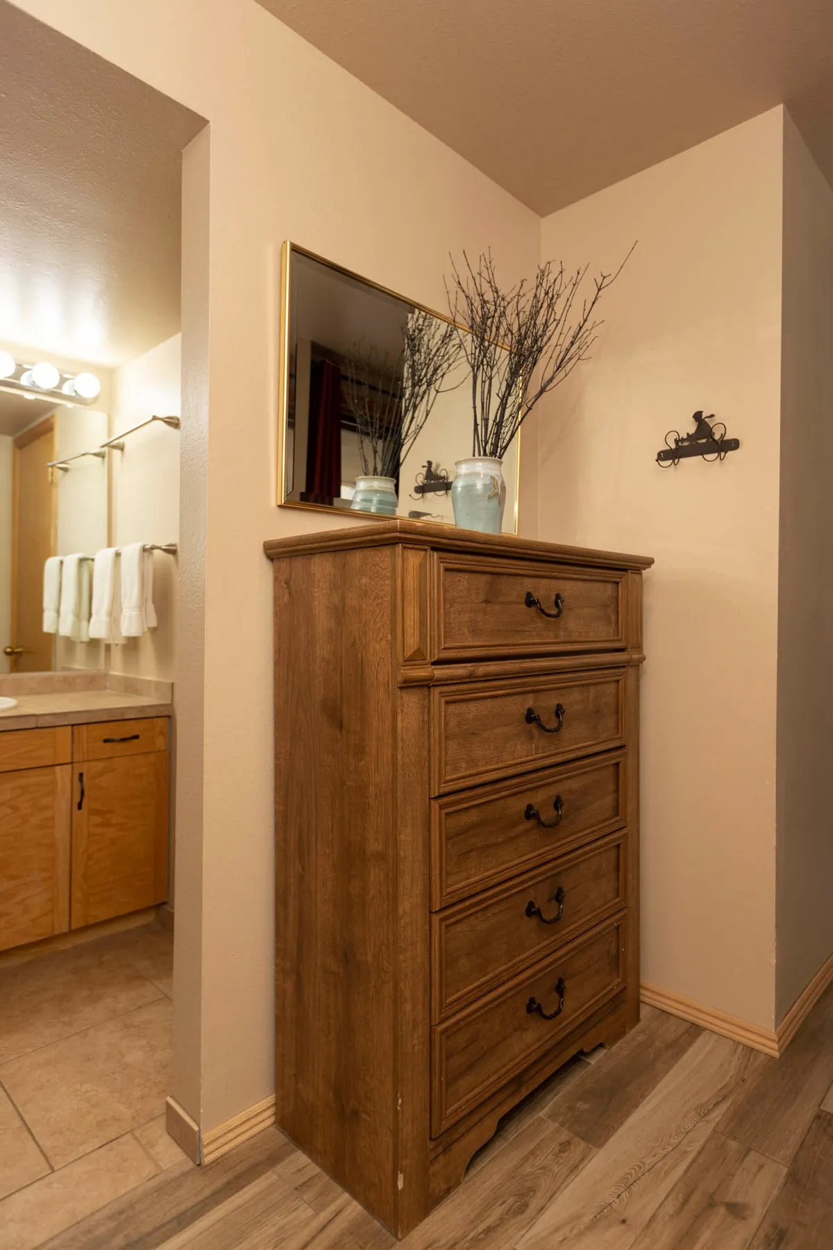 A stylish wooden dresser topped with a mirror and decorative natural branches. The dresser offers ample storage for personal belongings, while the mirror and decor add a touch of elegance and functionality to the bedroom setting.
