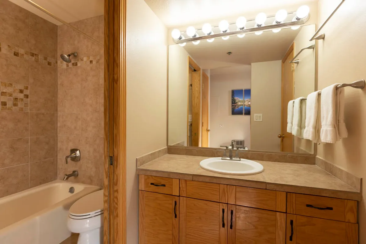 A well-equipped bathroom featuring a modern vanity with sink, large mirror, shower area, toilet, and elegant light fixtures. The space is clean, bright, and inviting—ideal for privacy and daily routines.